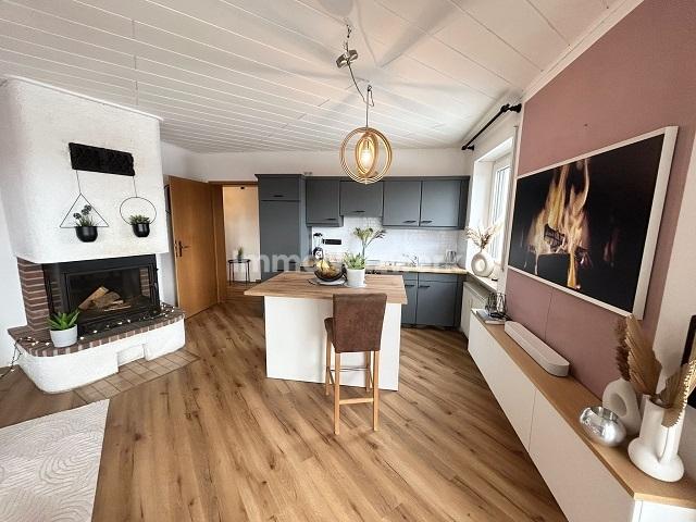 Wohnzimmer mit Kamin und offener Küche