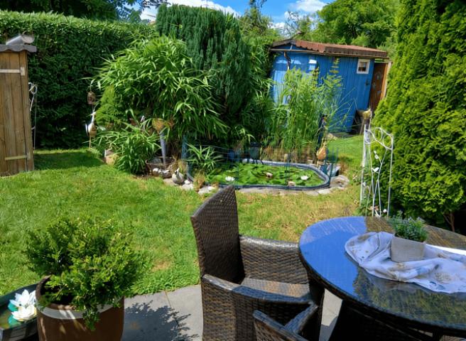 Sonniger Garten mit Teich und Laube