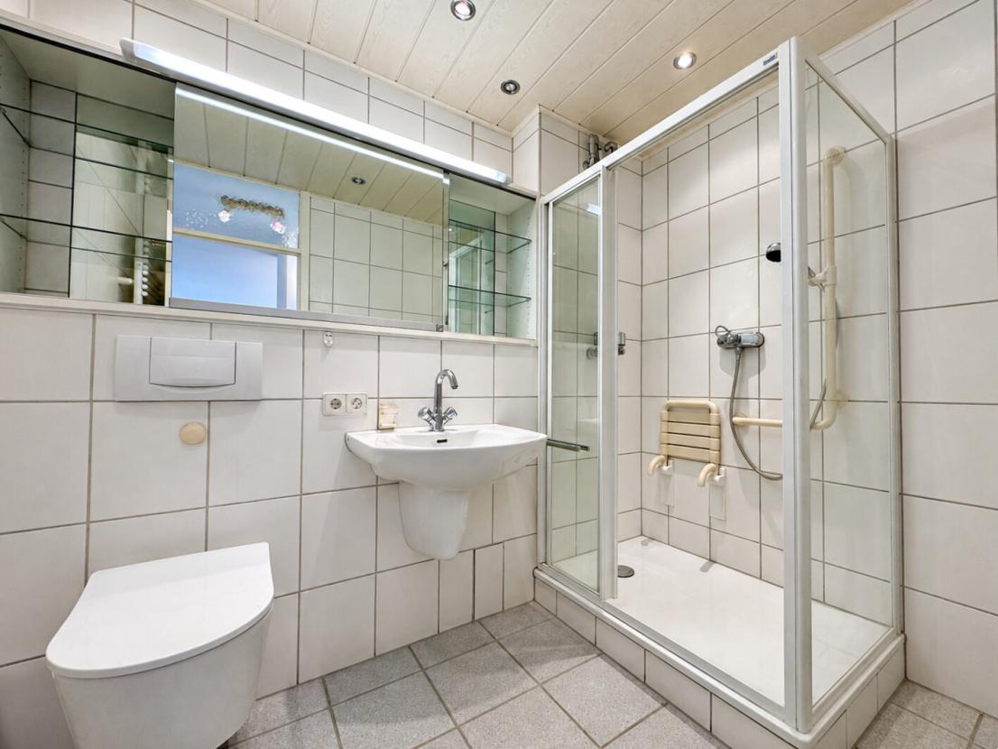 Gefliestes Badezimmer mit Dusche und WC