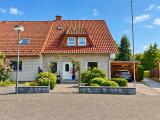 Sonniger Vorgarten mit Backsteinhaus und Carport